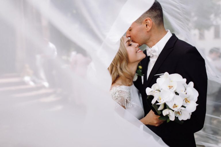 optimize- groom-black-tuxedo-hugs-tender-stunning-bride-while-they-stand